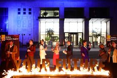 Greenpeace activists dressed as Shell board members hold a mock Shell profits party behind a burning sign reading "Your Future" during a protest outside Shell's headquarters in London on February 1, 2024, on the day that the oil and gas company releases its annual results