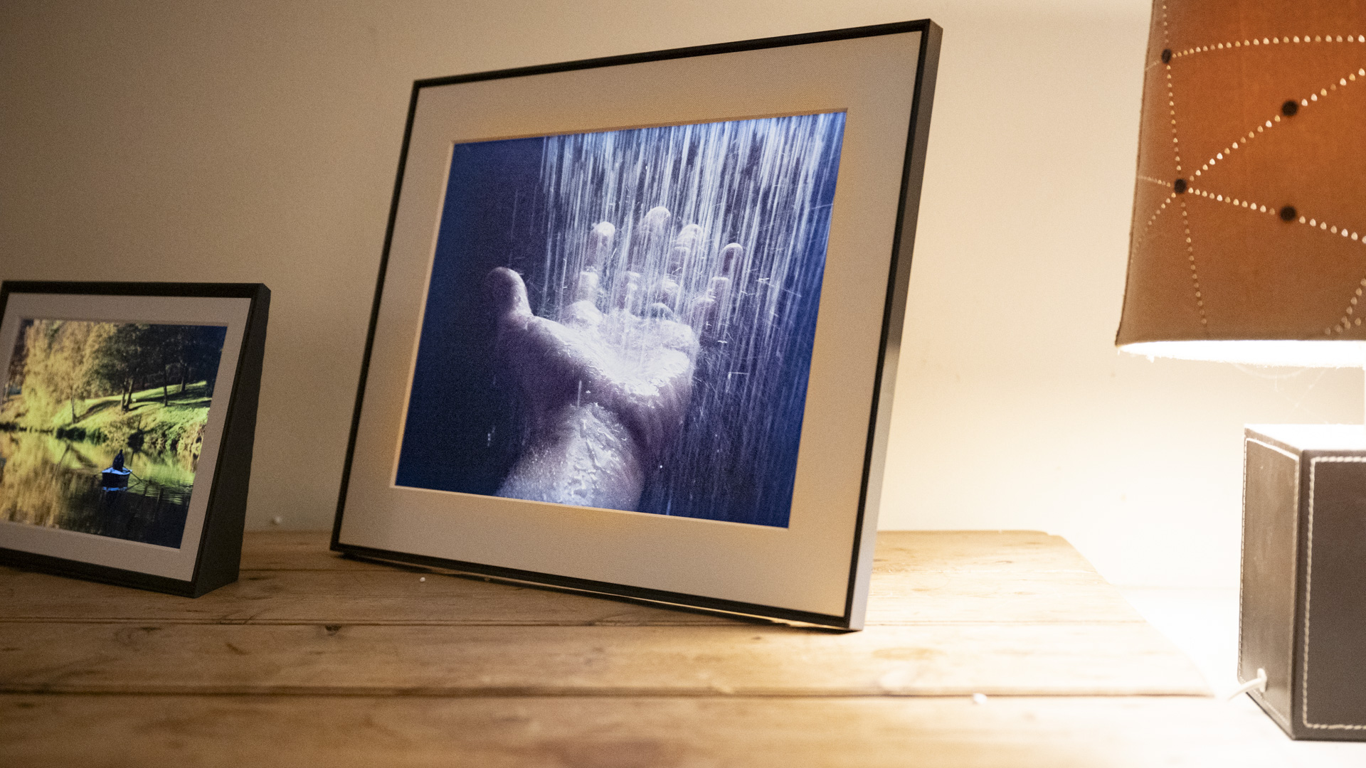 Aura Walden digital photo frame on a wooden sideboard at nighttime