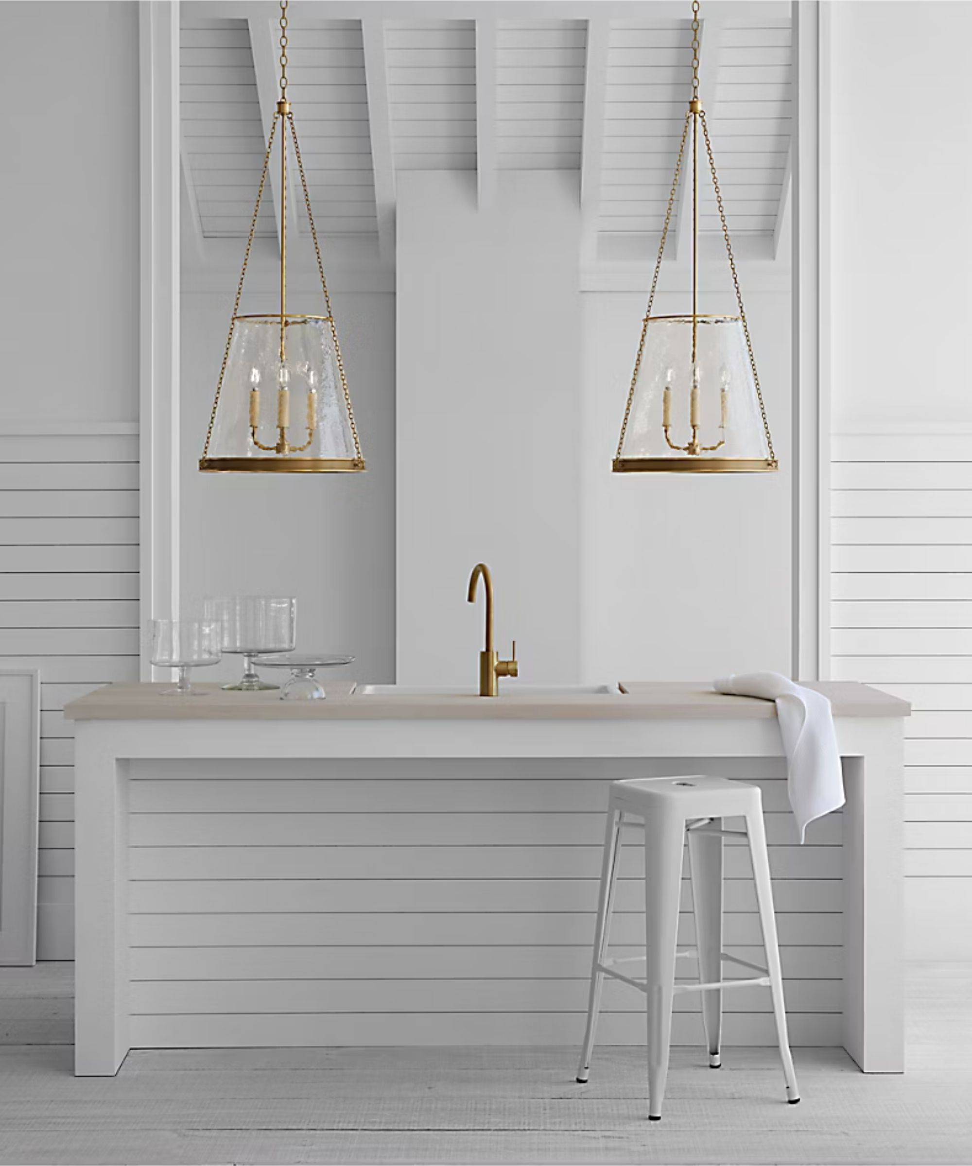 A white coastal kitchen with brass pendant lights from Visual Comfort