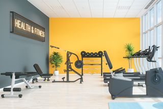 home gym with yellow and grey walls and a neon sign