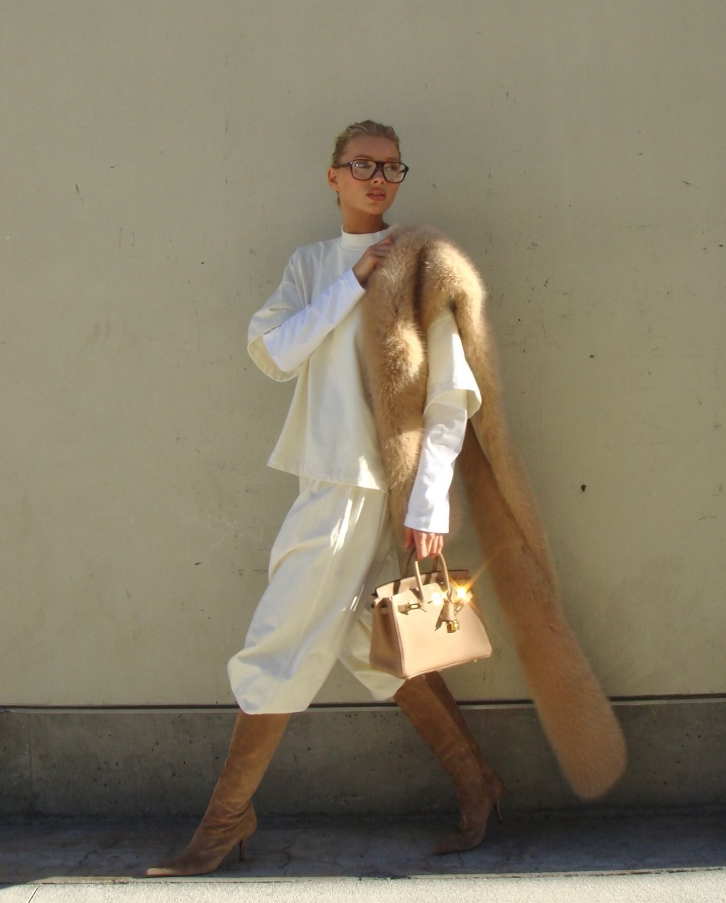 Elsa Hosk wearing a butter yellow sweatshirt and sweatpants with tan boots, a tan fur scarf, and a tan Birkin bag.