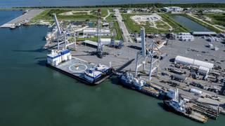 an overhead view of a dock in a sheltered cove, with several large ships moored