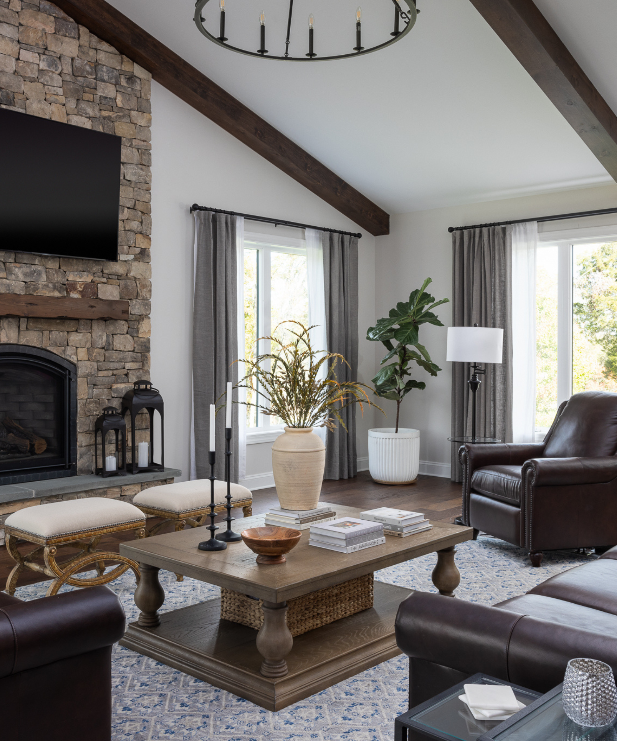 A white and brown living room with lofted ceilings and a stone fireplace