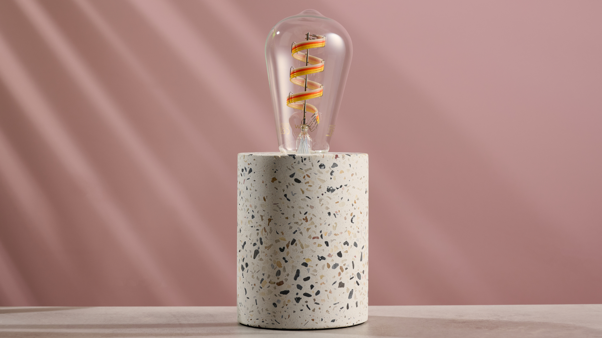 The WiZ filament bulb is pictured switched off on a concrete lamp.