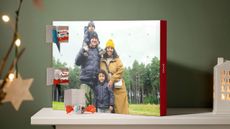 An advent calendar with a family photo on the front has kinder chocolates behind opened doors.