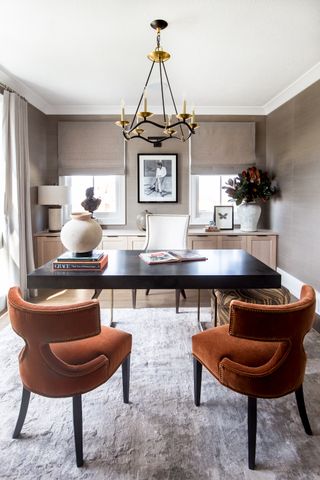 Home office with central desk and orange velvet chairs