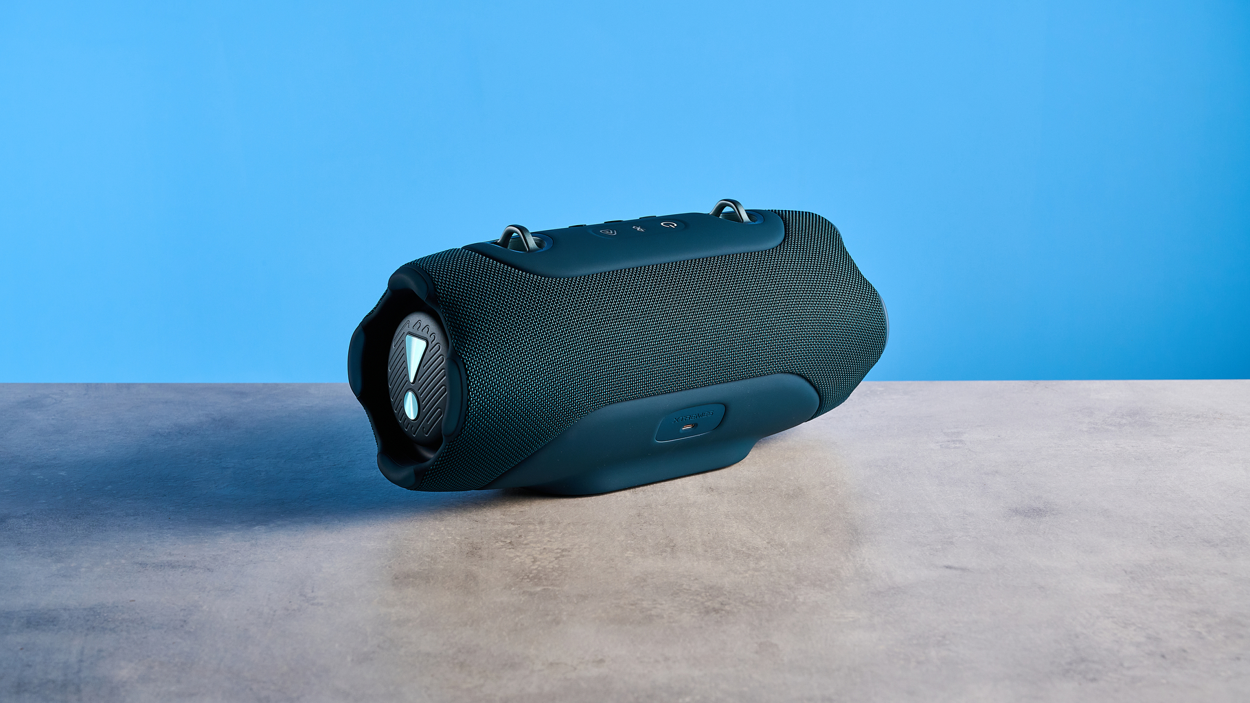 the JBL Xtreme 5 bluetooth speaker in blue shown with the rugged carry strap and buttons