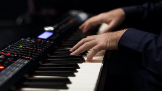 Close-up of hands playing a Roland stage piano
