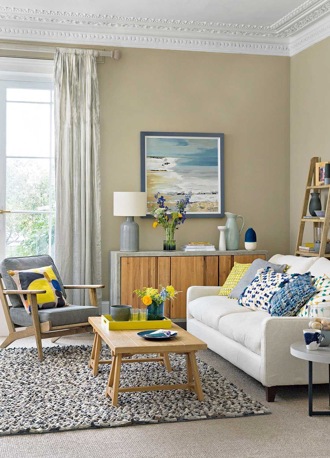neutral taupe living room with blue and yellow accent coloured accessories on armchair and sofa