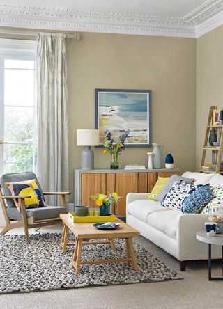 neutral taupe living room with blue and yellow accent coloured accessories on armchair and sofa