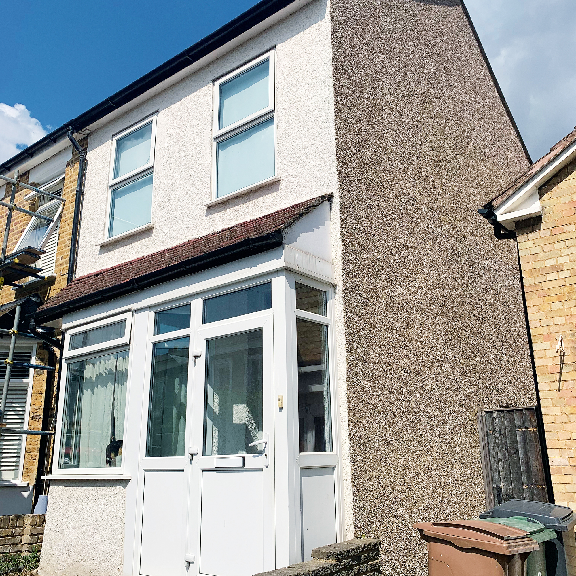 The front elevation of a pebble-dashed terraced house