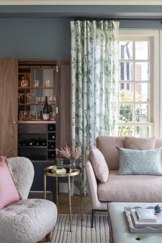 freestanding home bar in living room with doors, pink couch, armchair, rug, green coffee table and curtains, blue walls, side table