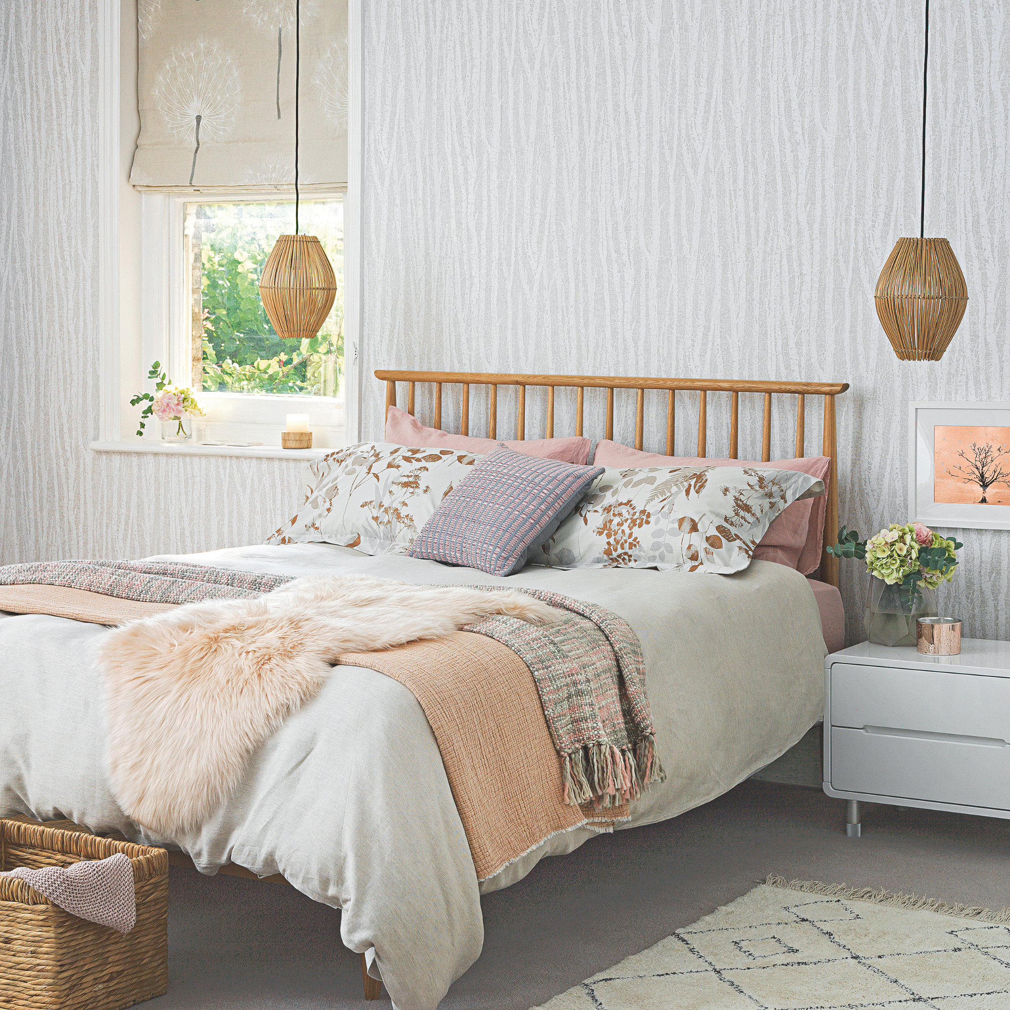 A modern cosy bedroom, with warm grey tones, pendant lights and double bed, grey wallpaper and soft muted coloured bedding, lilac and pink, sheepskin and floral pattern pillow cases.