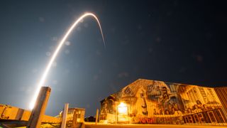 a time lapse image of a rocket launching over a building with a space-themed mural