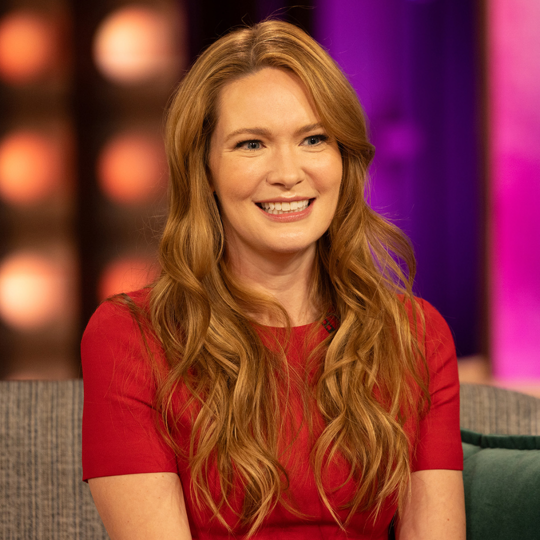 sarah j maas smiling and sitting on a couch at the kelly clarkson show