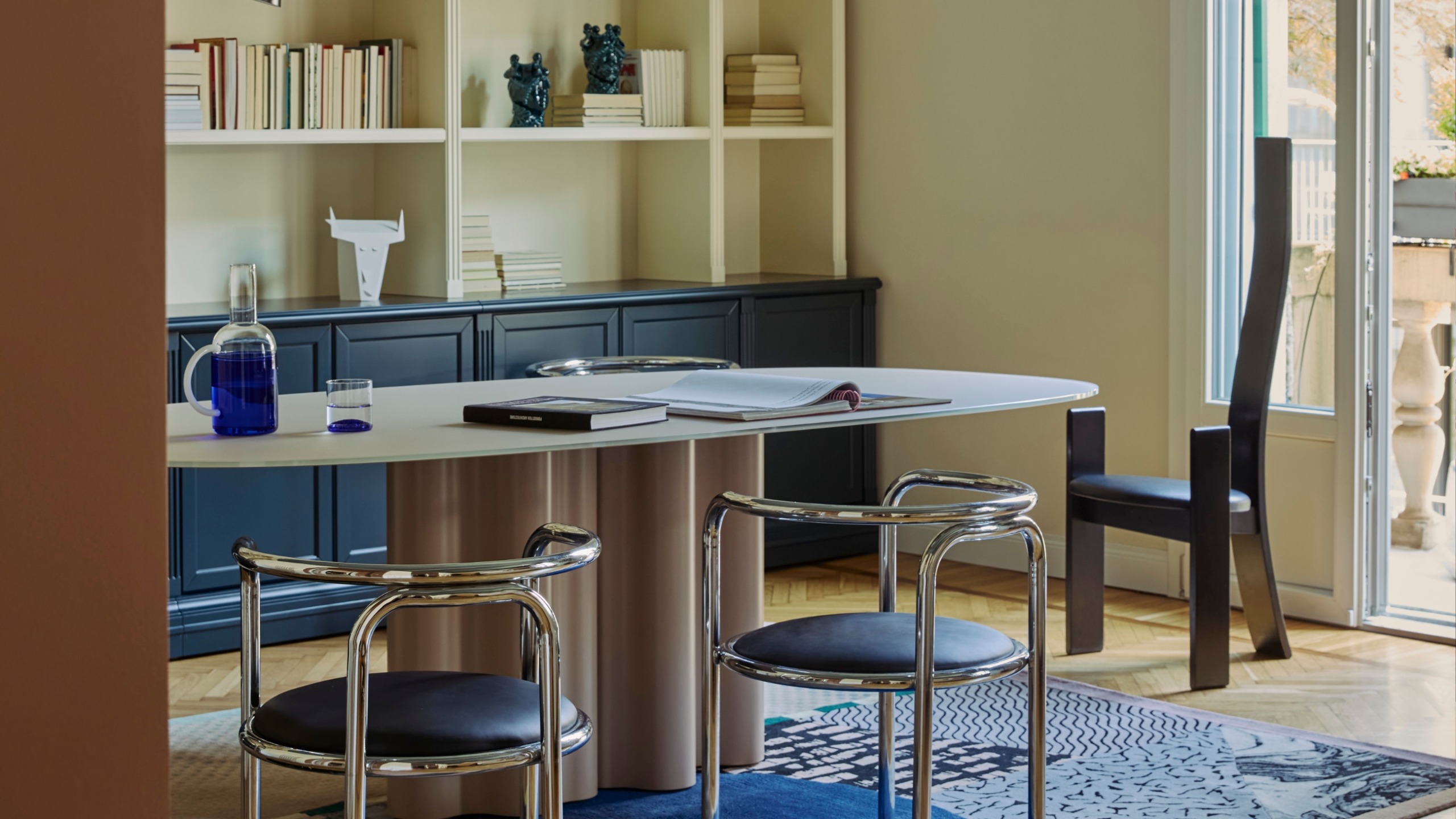 a dining room with metal tables and a sculptural black chair