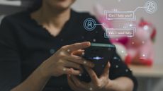 A person looks at their phone. The image is overlaid with graphics showing a chatbot.