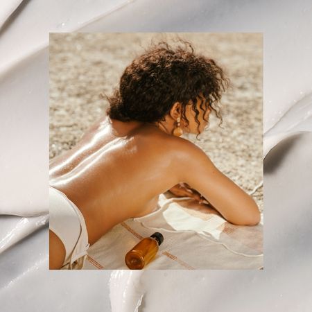 a woman lying on her stomach in the sun next to a bottle of sunscreen