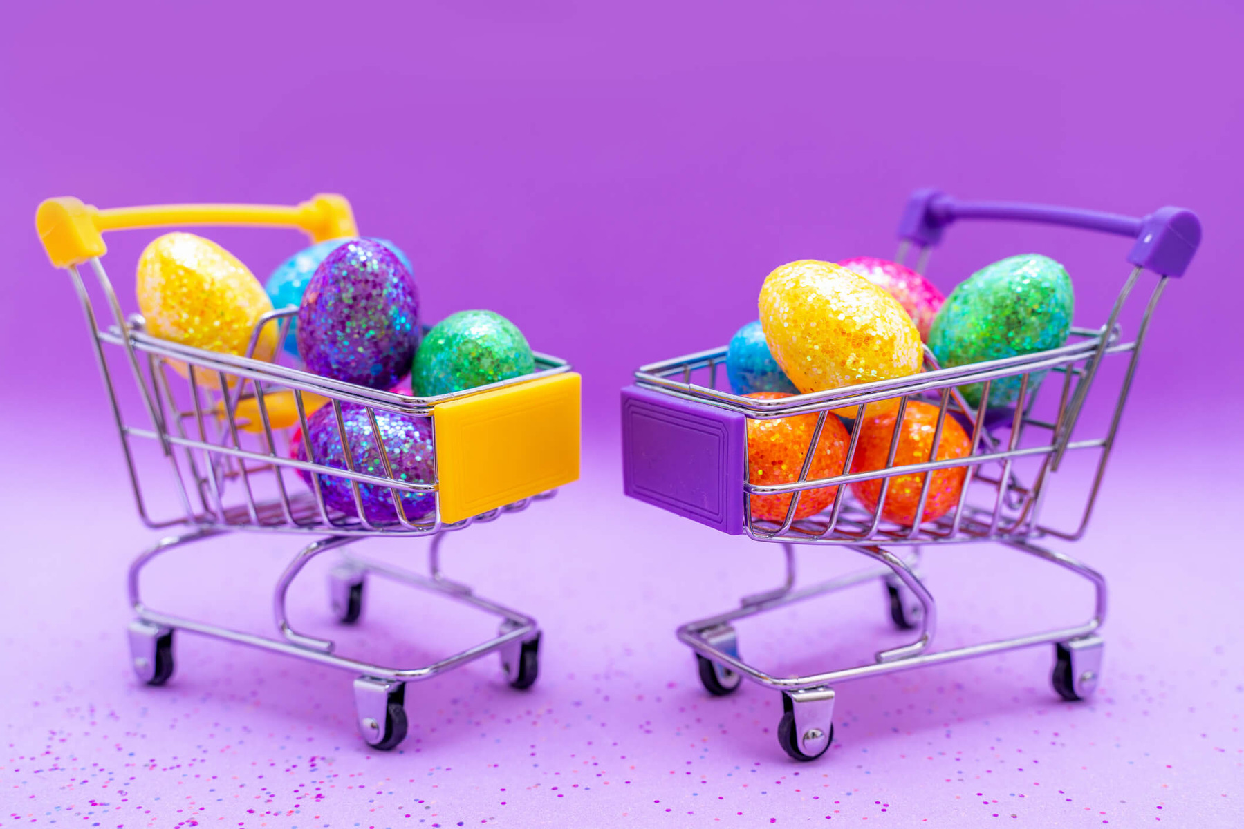 Two miniature shopping trollies are full of small easter eggs