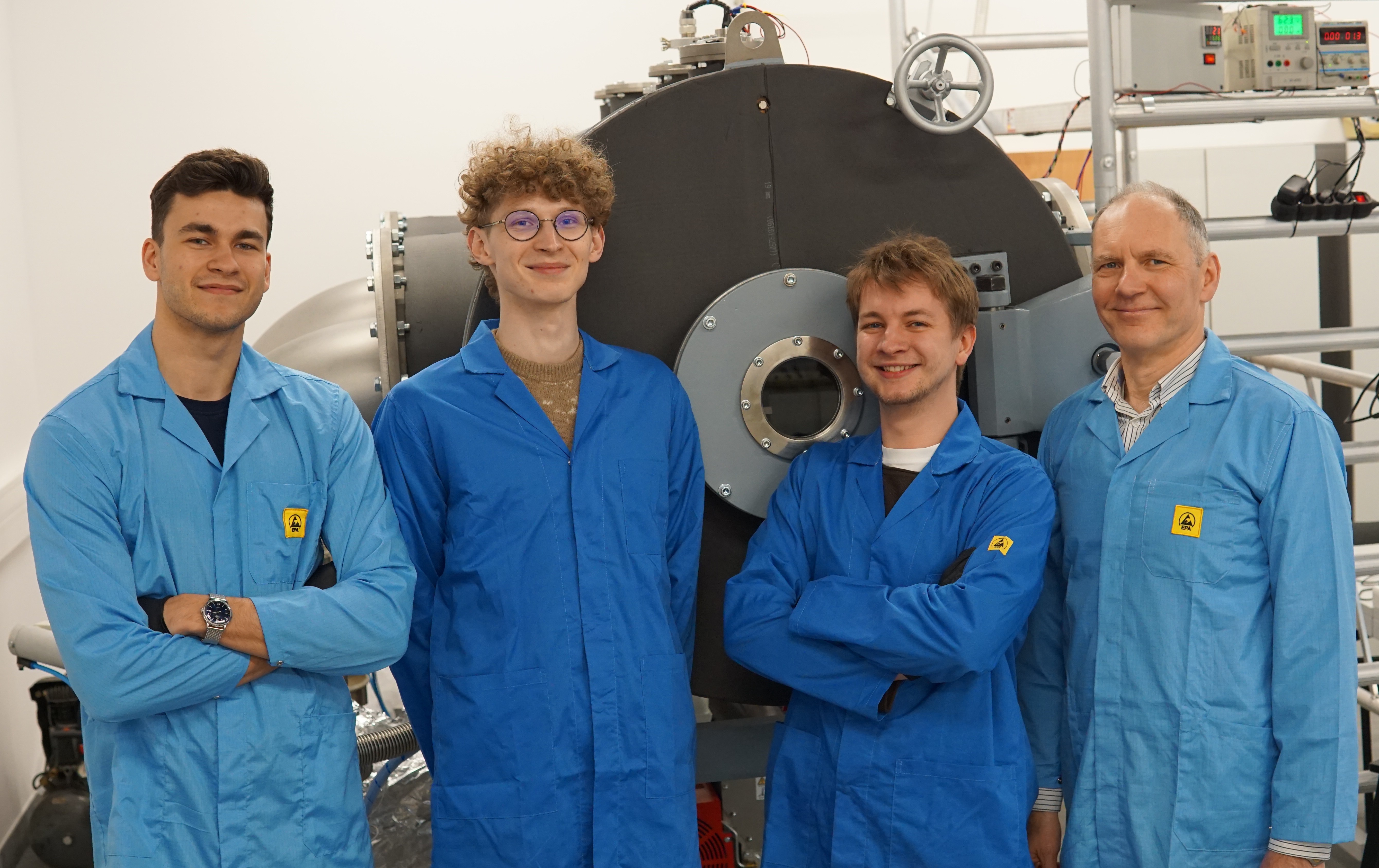 People standing in blue jumpsuits with their arms crossed.
