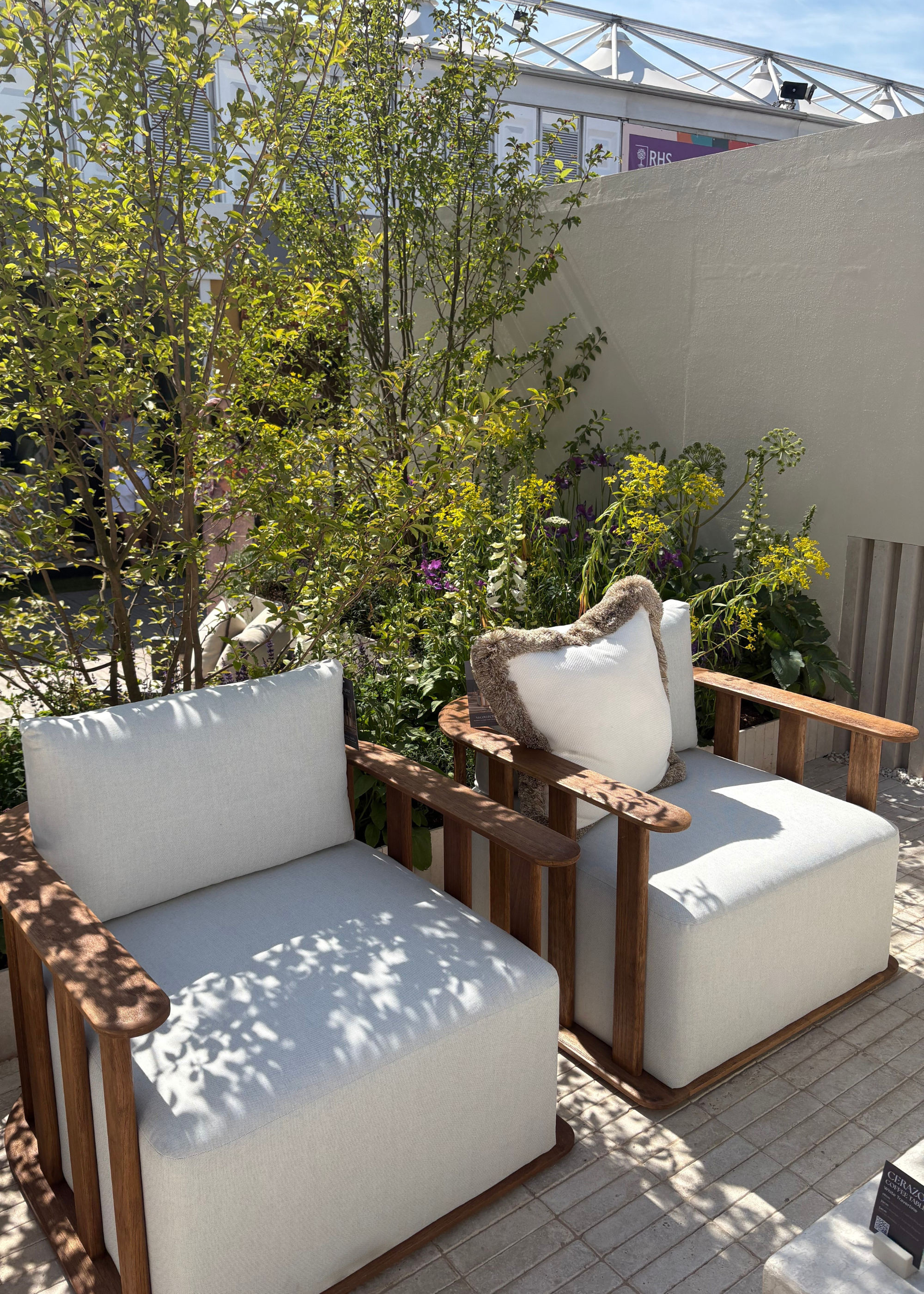 Nth Degree's exhibit at the Chelsea Flower Show 2025 featuring a pair of wooden outdoor sofa chairs