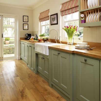 cream kitchen with soft green painted cupboards, wooden floors and countertops