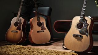 Three Gibson acoustic guitars in a dark living room