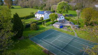 Aerial short of a large home with a tennis court