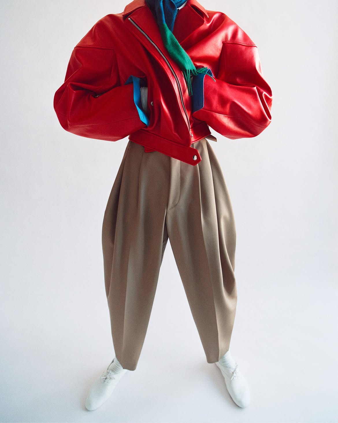 Celine model wearing a red leather jacket with beige trousers and white derby shoes