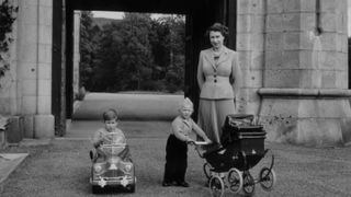 Queen Elizabeth walking with her children, Charles and Anne in the grounds of Balmoral Castle in Scotland