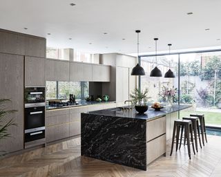 Open plan kitchen ideas illustrated in a gray scheme with full length windows and herringbone wooden flooring.