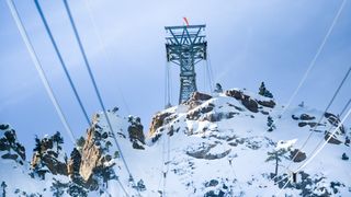 View of snowy mountainside and cable car tower as seen from inside cable car