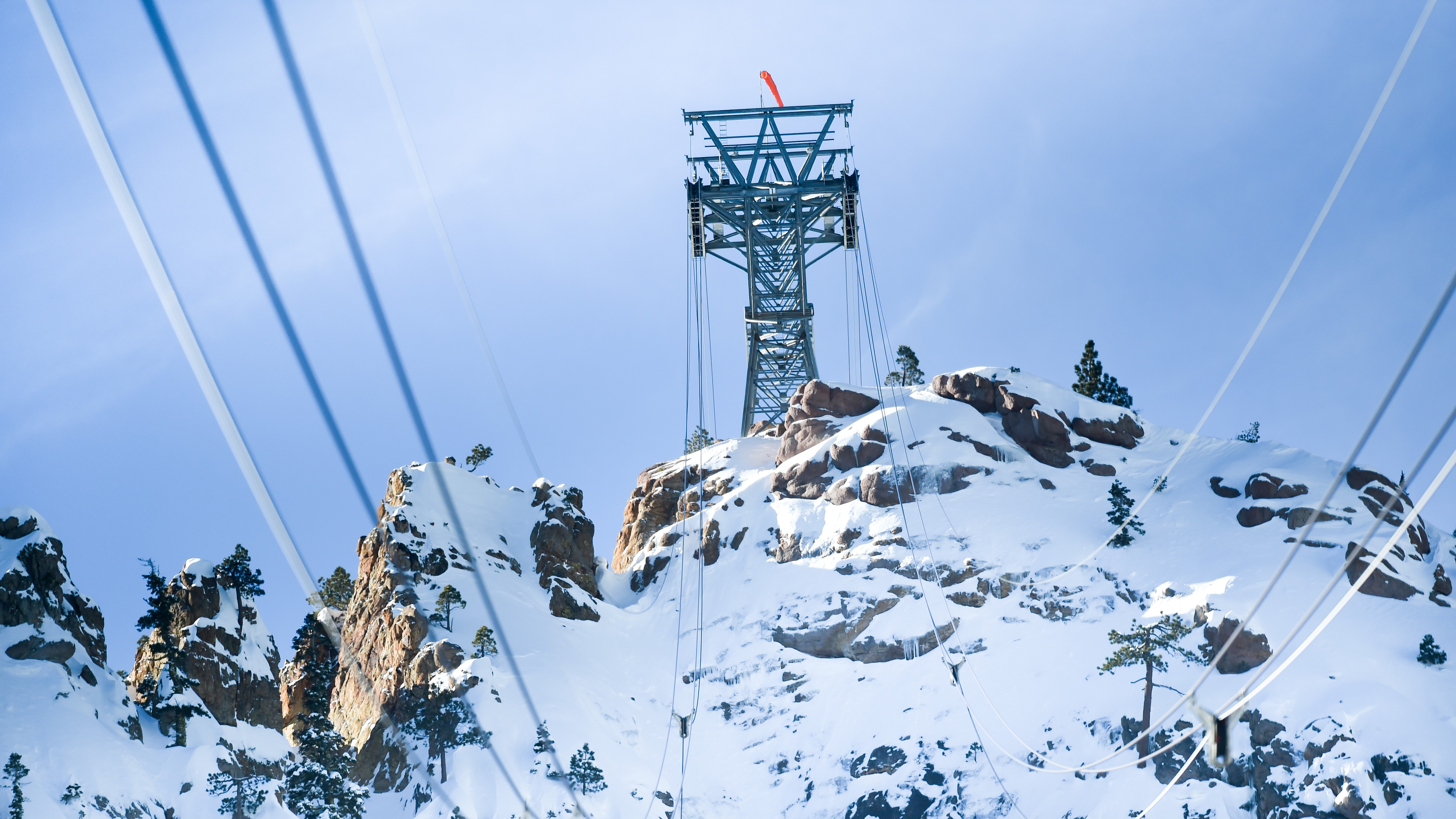 View of snowy mountainside and cable car tower as seen from inside cable car
