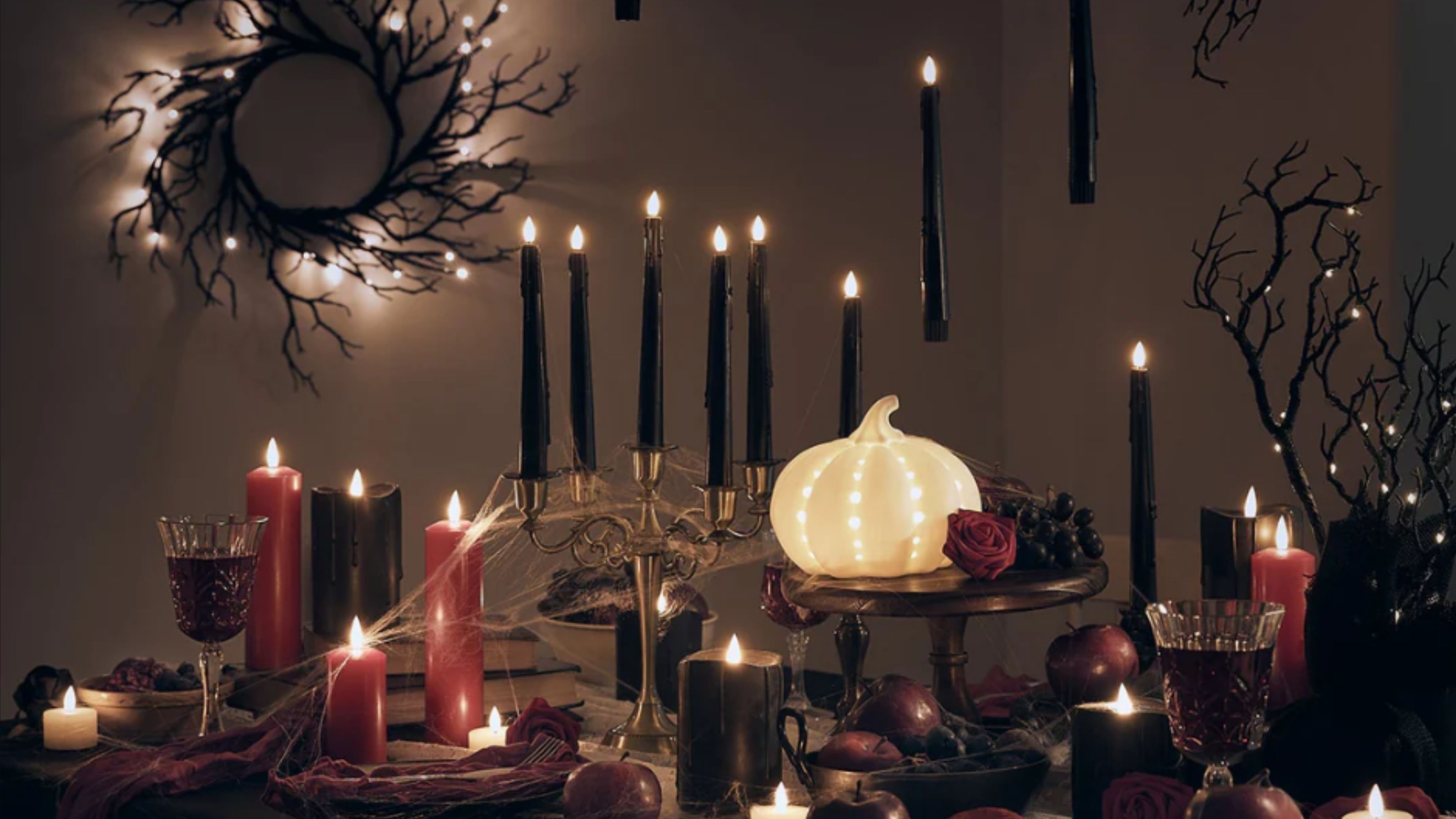 A gothic, Halloween table set up with black candles, and an LED pumpkin from Lights4Fun.