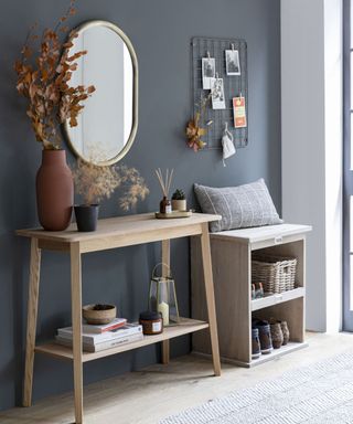 A blue entryway with a mirror, wooden console table, and shoe storage