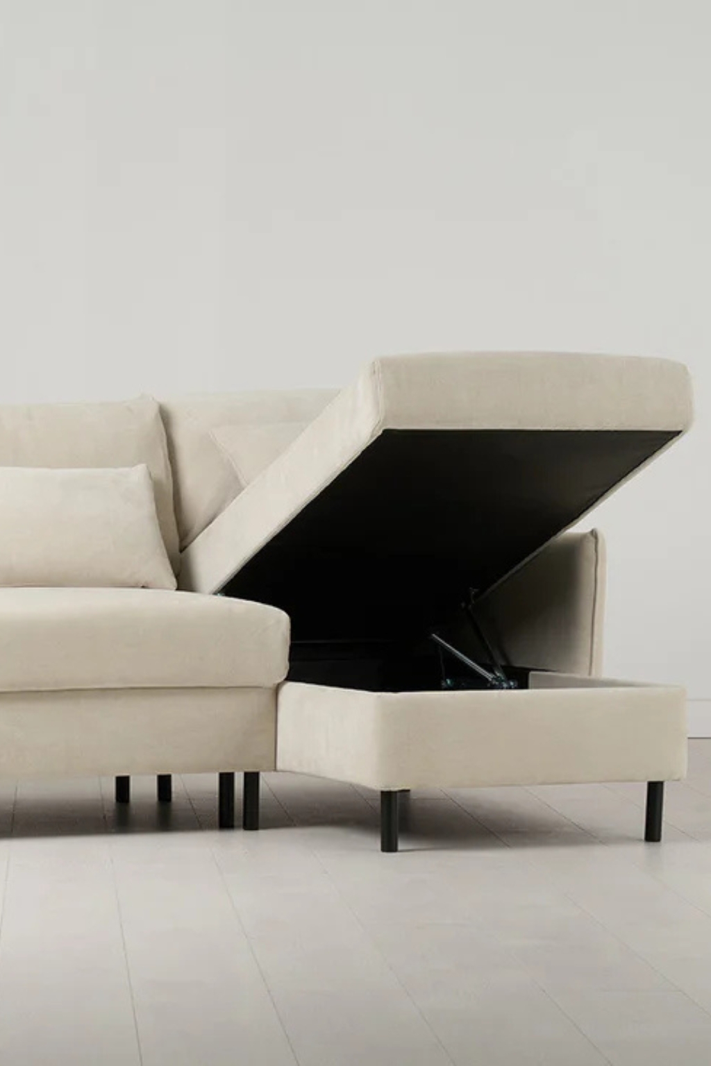 Image of an off-white sofa with the chaise lounge bit lifted to show hidden storage.