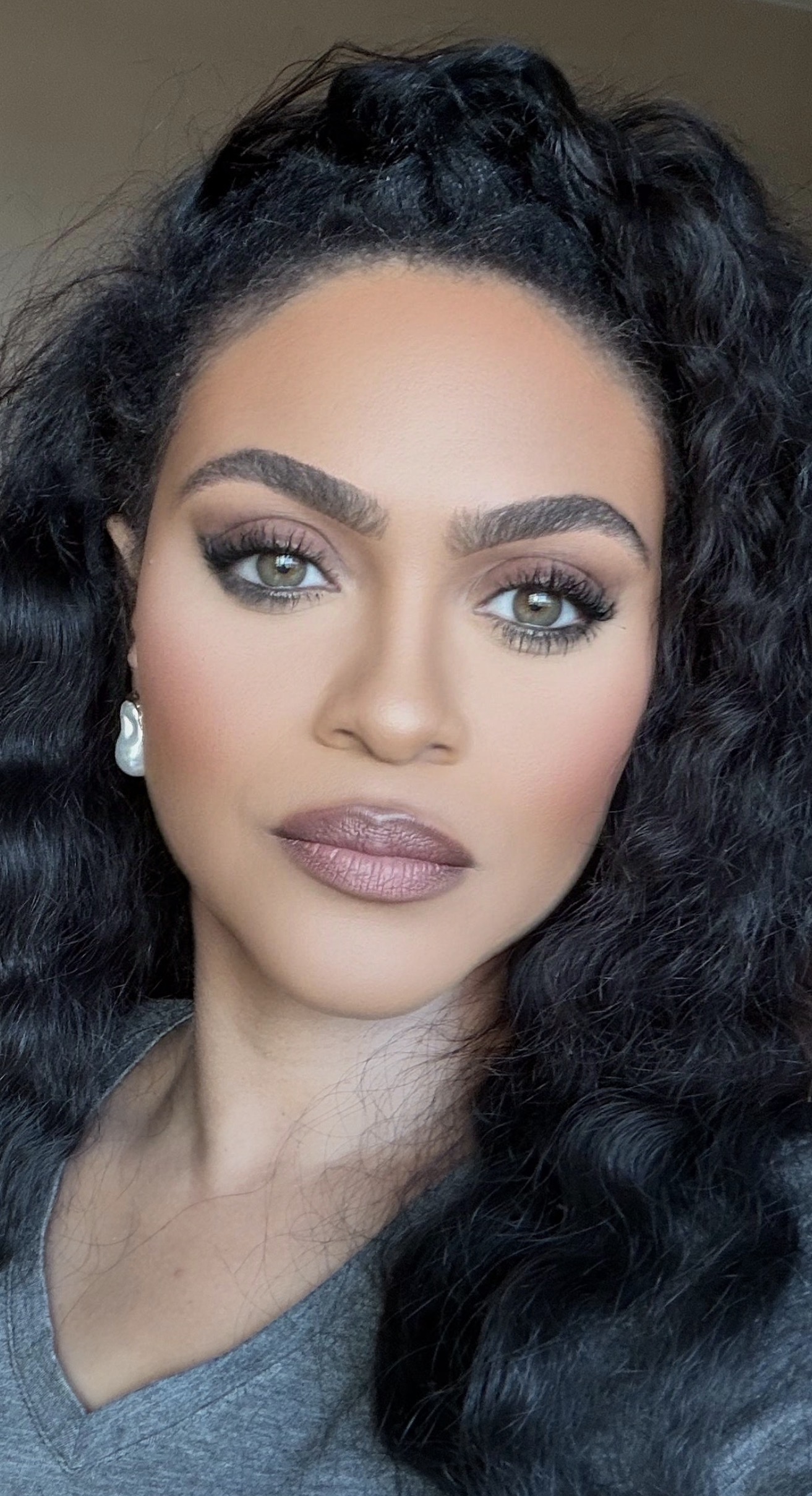 a woman with tan skin and smokey eye makeup and dark curly hair
