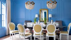 dining room with blue paneled walls and white chairs