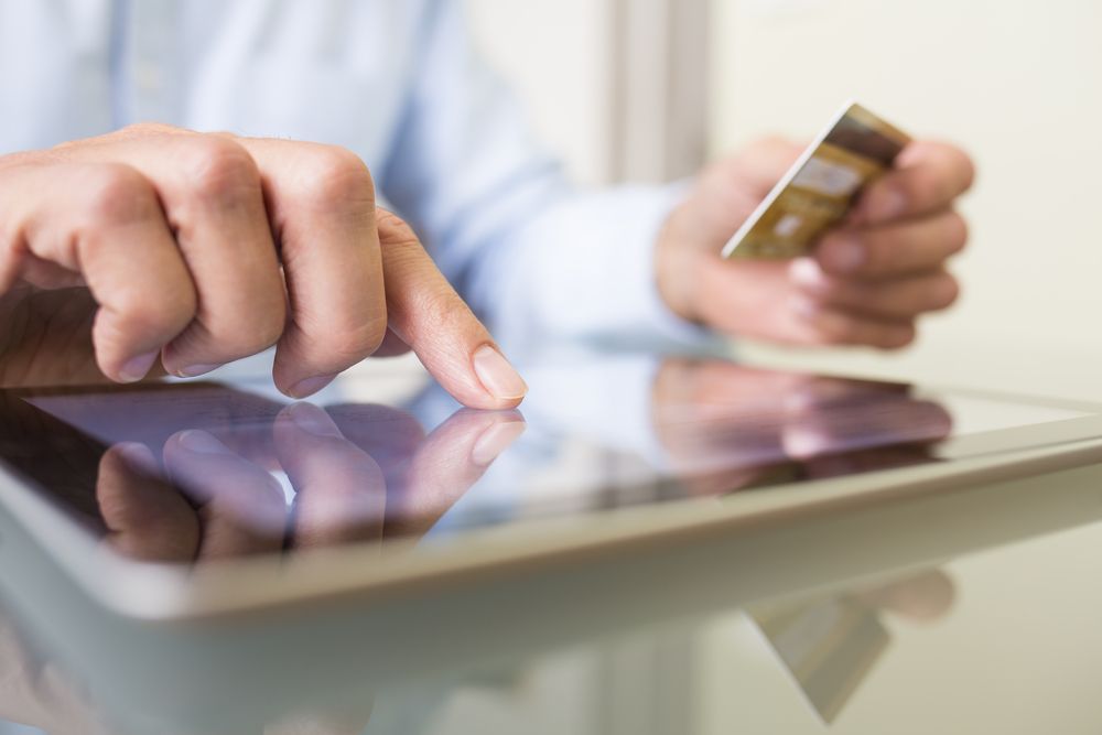 Man holding credit card making online payment on a tablet