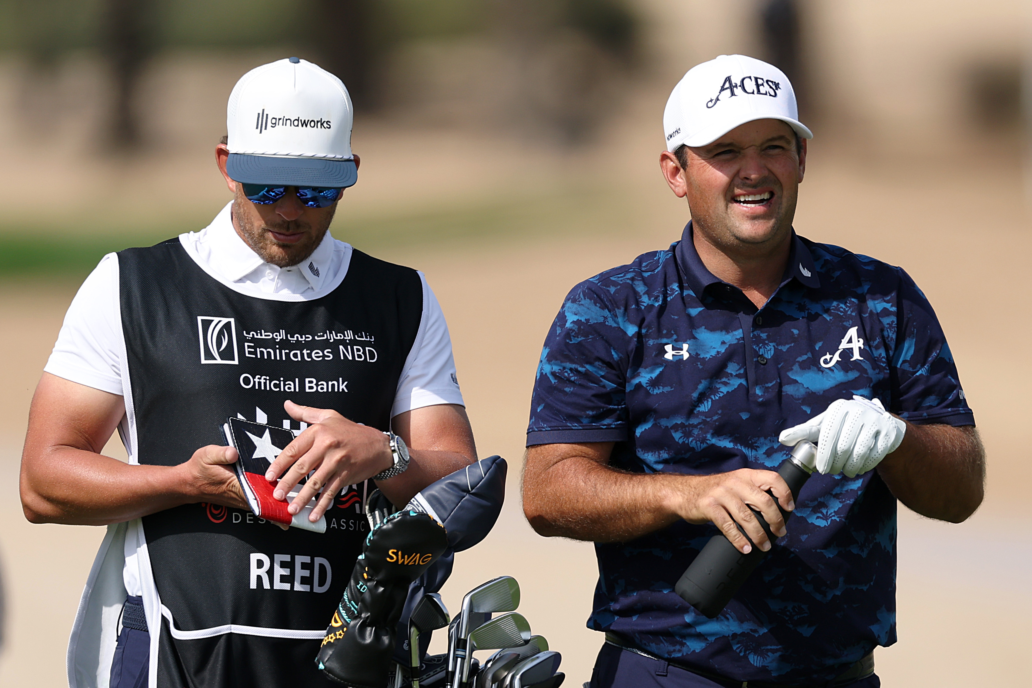Patrick Reed looks on with his caddie