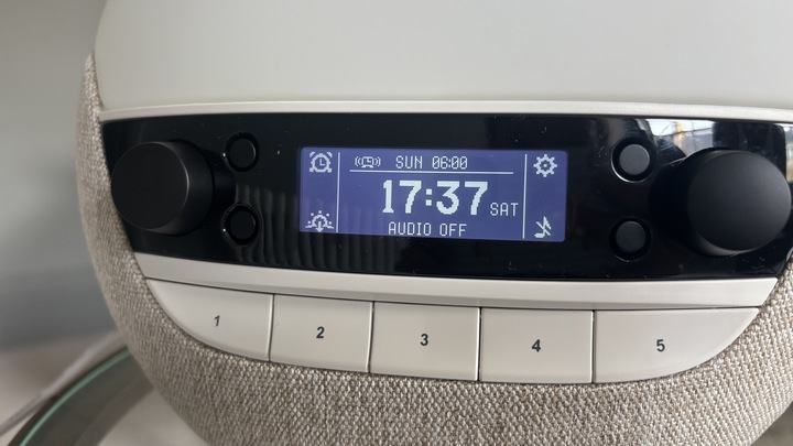 A close-up shot of the Lumie Bodyclock Luxe 700FM sunrise alarm clock's screen displaying the time, day of the week, and next alarm. 