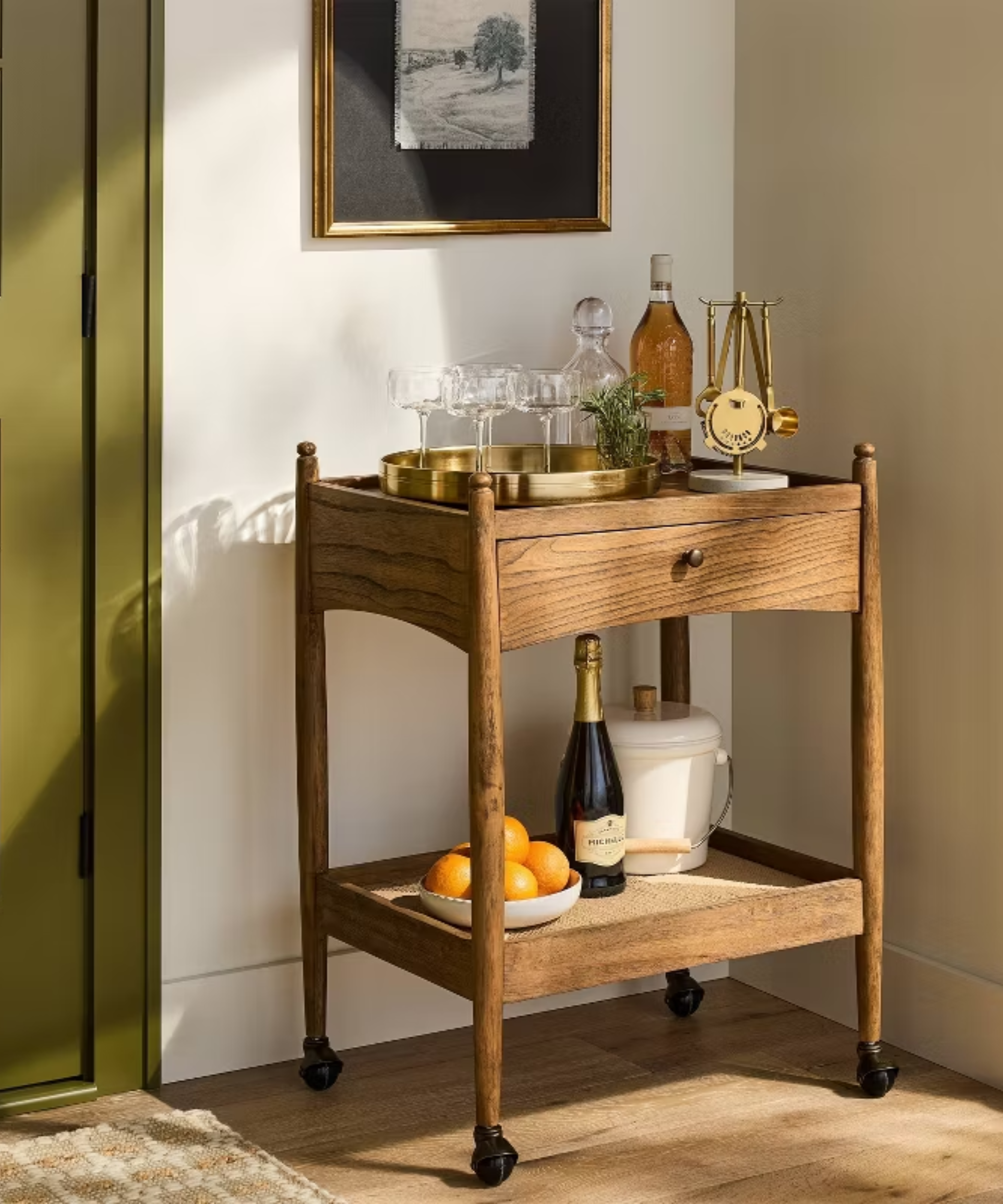 a wood bar cart with drinkware and bottles on it