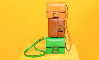 View of three Fendi Fab bags in orange, brown and green stacked on top of each other on a yellow surface in a space with a yellow background