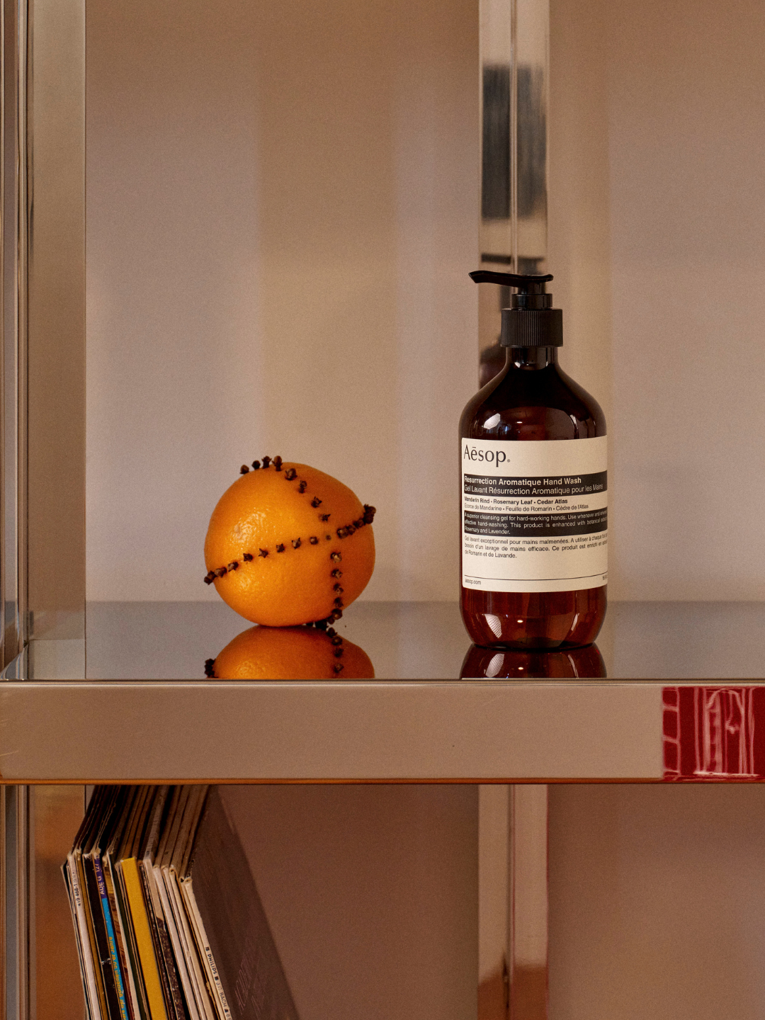 A bottle of hand wash from Aesop beside a clove-studded orange