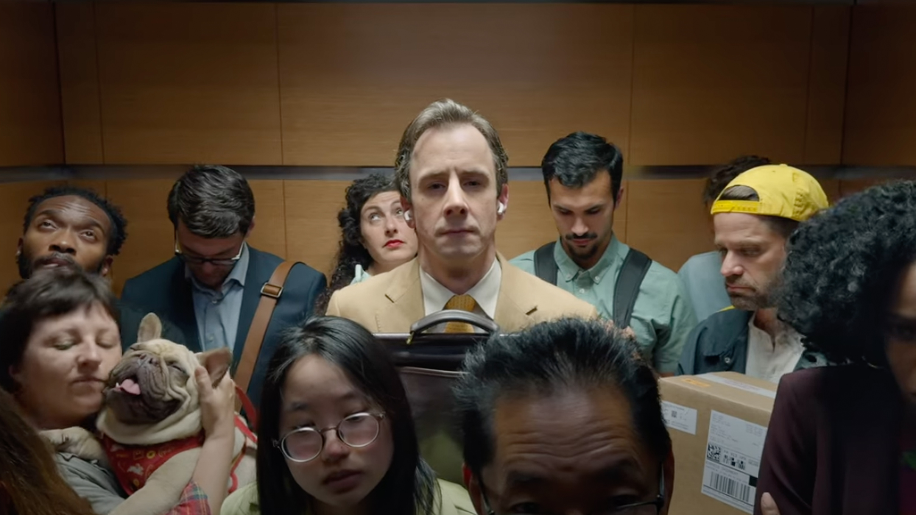 A man stands in an elevator with AirPods in his hands