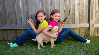 Two sisters playing on phone with chihuahua not interested