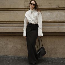 Lena wears white buttond down and black column skirt with a black handbag and black sunglasses