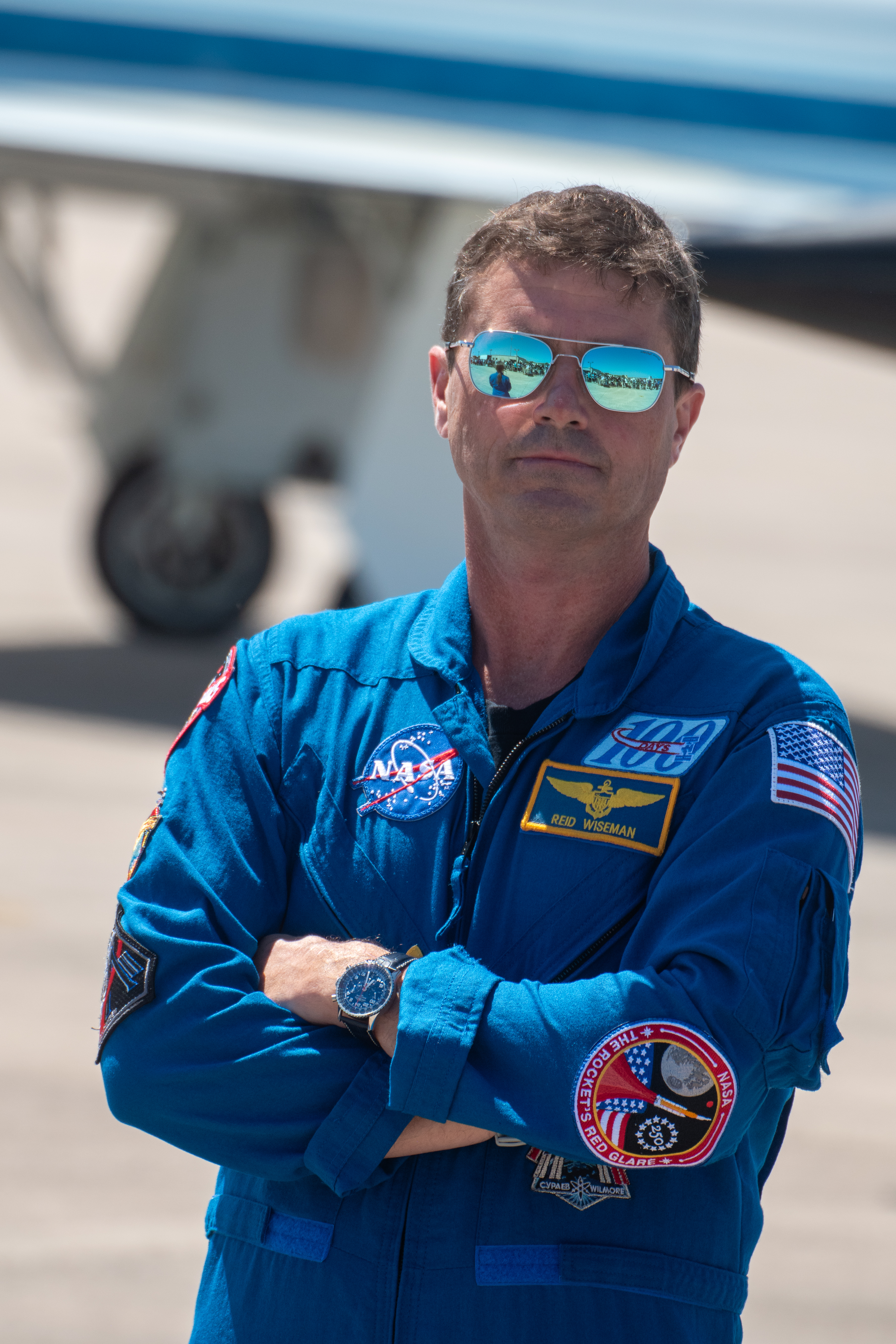 An astronaut in blue jumpsuit stands outside.
