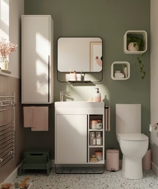 small bathroom with white cupboards, vanity unit, sink and toilet against green wall
