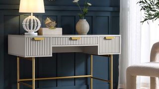 A close up of a grey dressing table against a dark blue pannelled wall